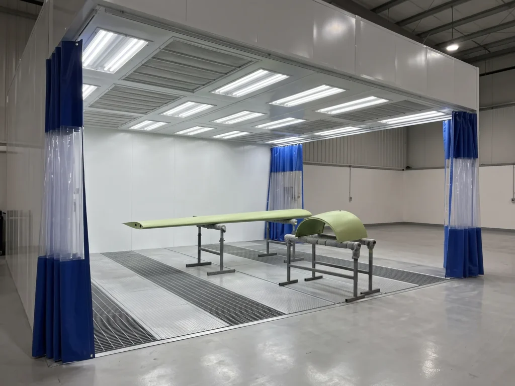 Light-aircraft wing surface and engine cowling in primer on stands inside a curtained prep station