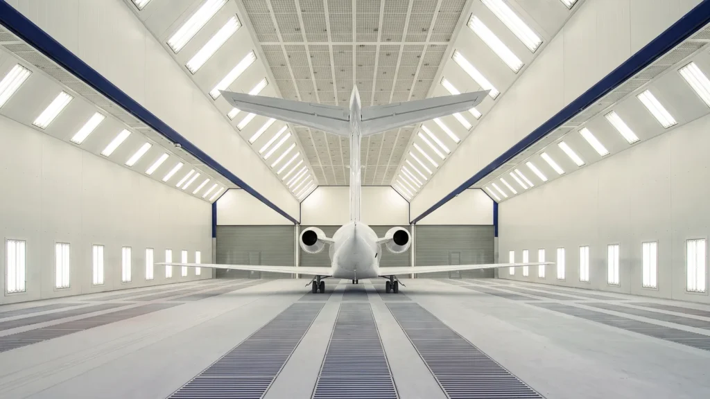 Small white business jet inside an aircraft paint booth