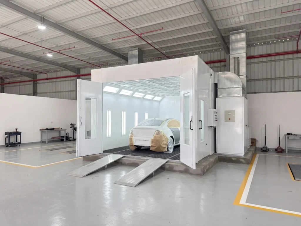 Paint booth at the end of a repair workshop with a masked car inside for a partial repaint