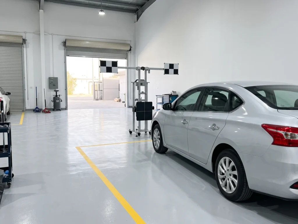 ADAS calibration frame in front of a silver car in a calibration bay at a collision repair centre