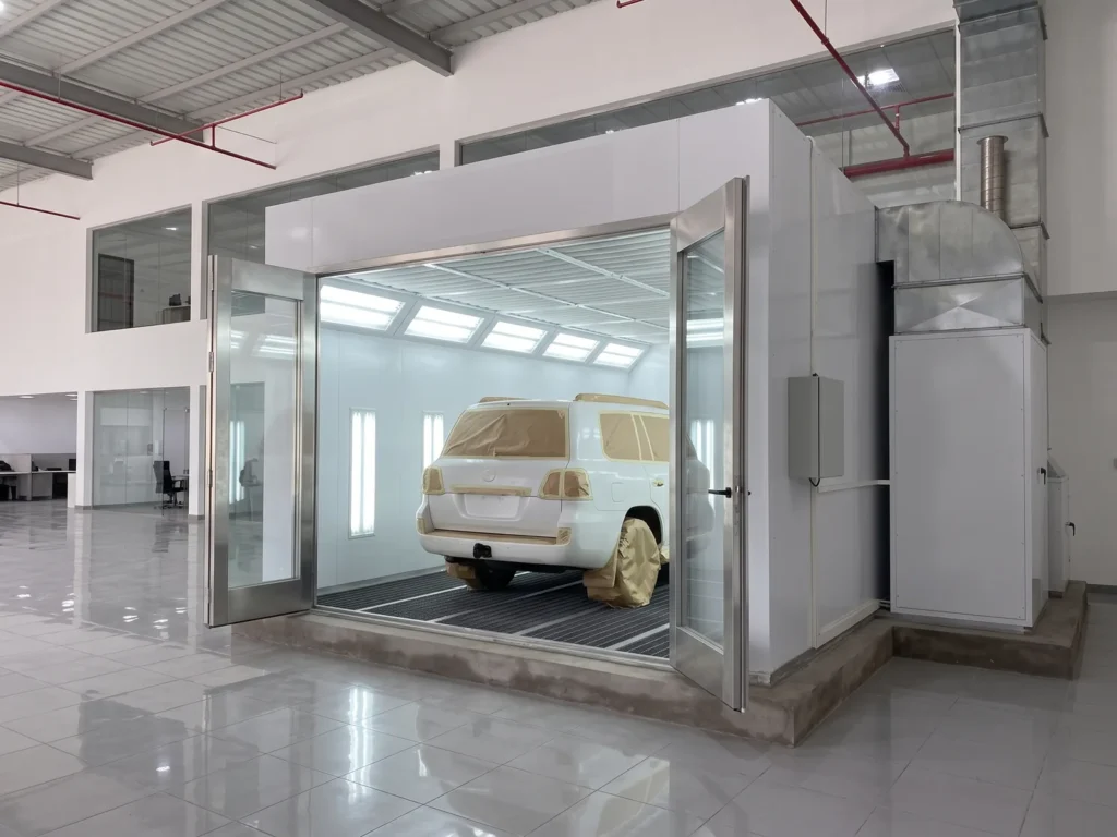 Masked SUV inside a paint booth with open doors in a dealership service centre