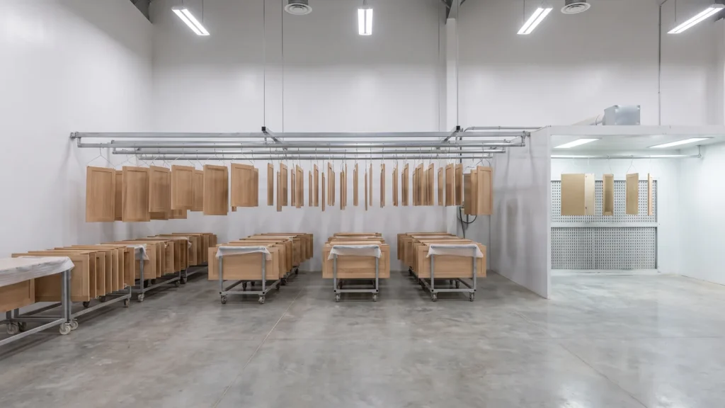 Wooden cabinet doors hung for finishing beside a spray booth in a furniture factory